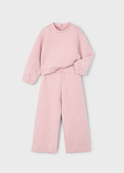 Pink quilted outfit with top and pants on a light gray background
