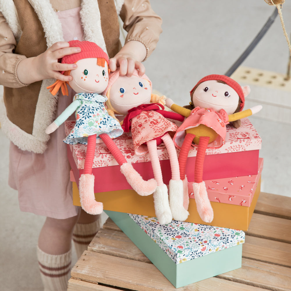 Lilliputiens Stella soft fabric doll with red hair, floral dress, fawn‑ear hat and decorative gift box.