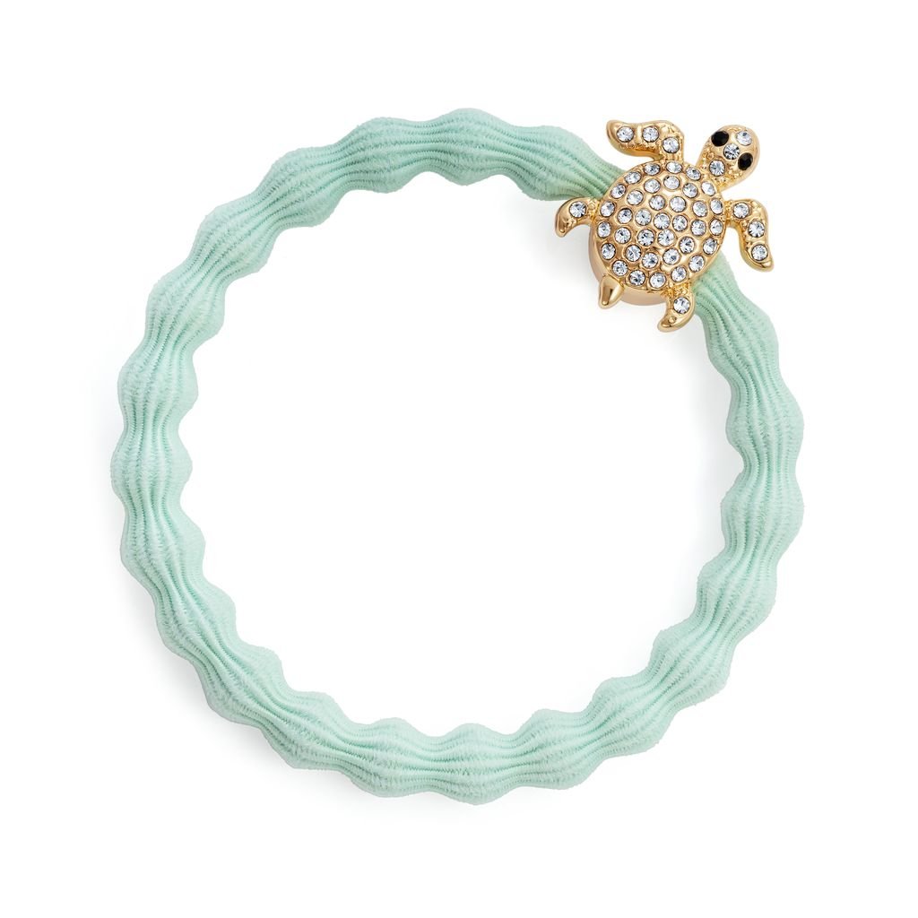 Mint green hair tie with a turtle charm on a white background