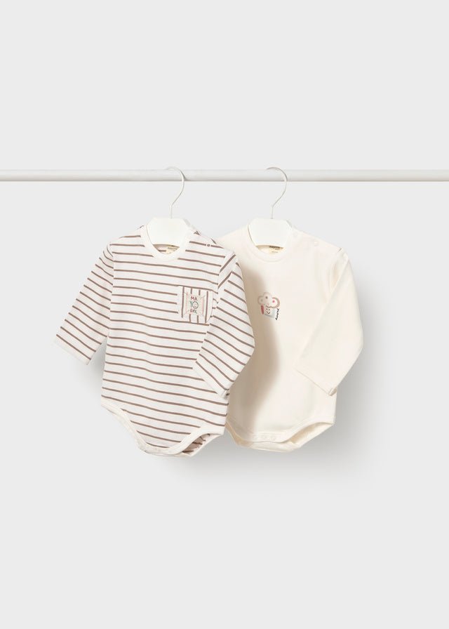 Two baby long-sleeve bodysuits hanging on white hangers from a horizontal rod. The left bodysuit is white with thin brown horizontal stripes and a small chest pocket.