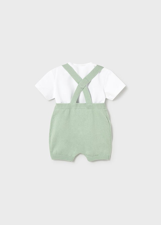 Baby green knitted romper with shoulder straps and white short‑sleeve t-shirt.