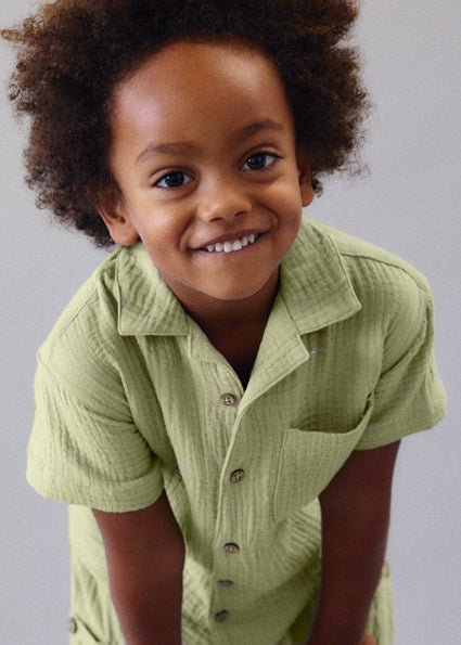 Boy wearing a Mayoral button up cheesecloth style shirt in a bamboo beige colour