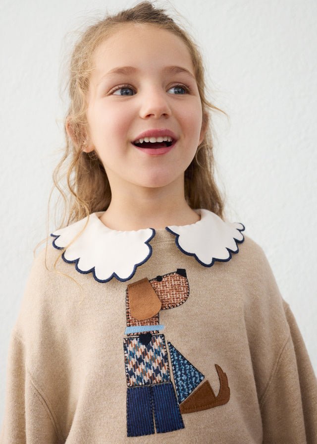 Child wearing a sweater with a dog design on a plain background
