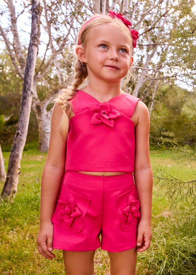 Girls’ bright pink crop‑top and shorts set with wide straps and soft front detail.