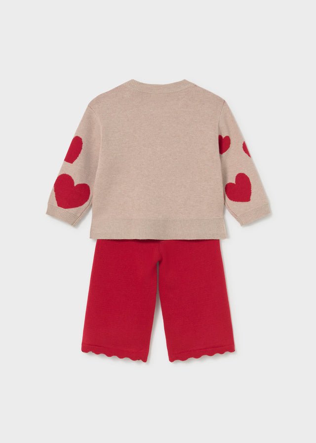 A toddler's two-piece knit outfit set featuring a beige sweater with red heart details on the sleeves and matching red pants with scalloped hems, shown against a light gray background.