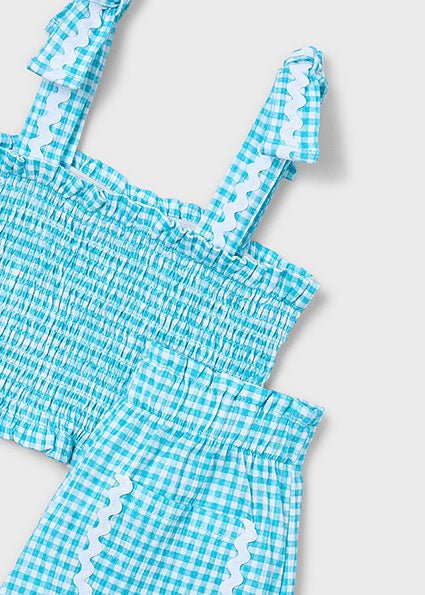 Girls’ blue and white gingham summer outfit with smocked ruffle-strap top and scalloped-pocket shorts.
