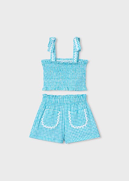 Girls’ blue and white gingham summer outfit with smocked ruffle-strap top and scalloped-pocket shorts.