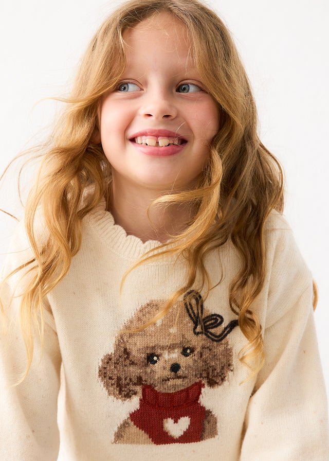 Young girl wearing a cream sweater with a poodle dog design on a white background