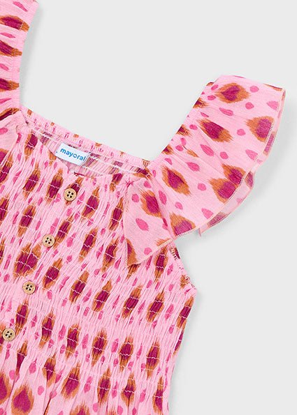 Pink girls’ sleeveless Mayoral top with smocked chest, ruffle strap, and wooden button front.