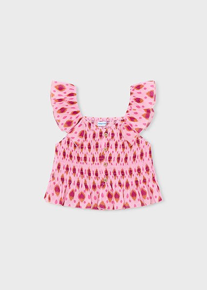 Pink girls’ sleeveless Mayoral top with smocked chest, ruffle strap, and wooden button front.