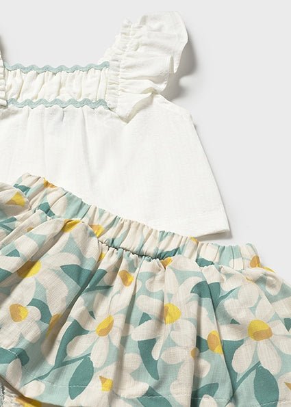 White ruffle strap top with ruching to the chest and floral print skirt with bloomer set on a light gray background