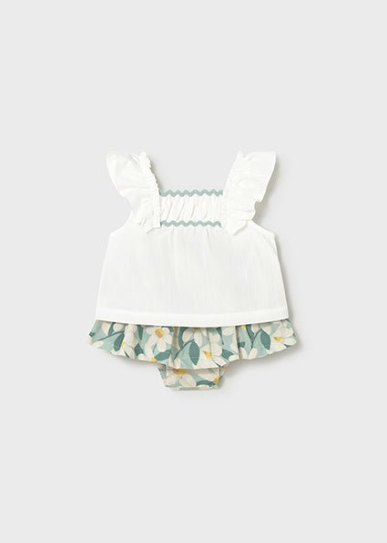 White ruffle strap top with ruching to the chest and floral print skirt with bloomer set on a light gray background
