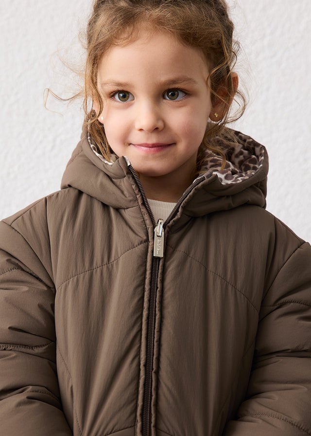 Child wearing a brown puffer jacket with a hood against a neutral background