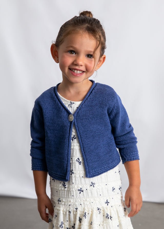 Blue knitted girls’ cardigan with single button closure and textured cuffs and hem.
