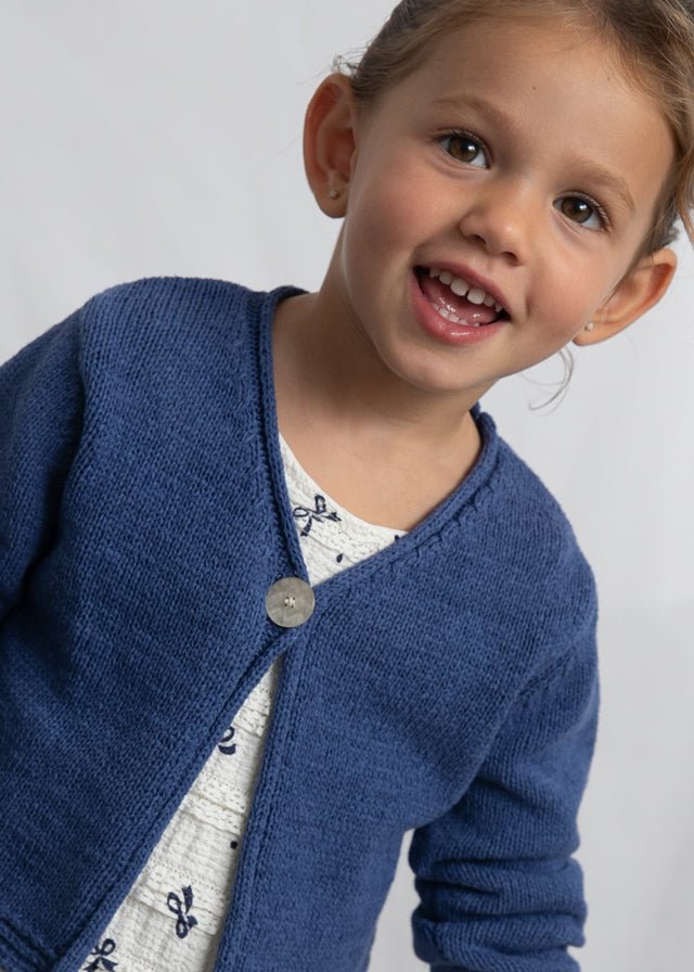 Blue knitted girls’ cardigan with single button closure and textured cuffs and hem.