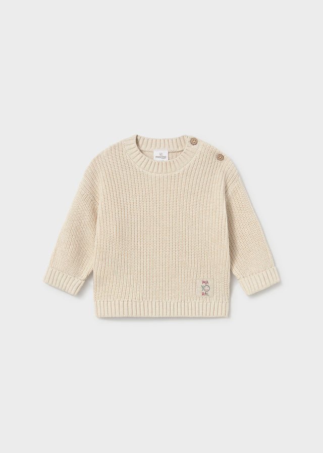 A cream-colored ribbed knit baby sweater with button details on the shoulders and a small embroidered logo on the lower hem, displayed against a light gray background.