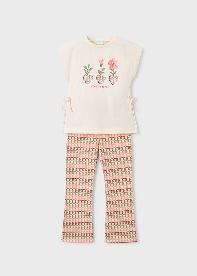 Girls’ two-piece holiday outfit with beige printed top and flared patterned trousers in soft pink, green, and beige.