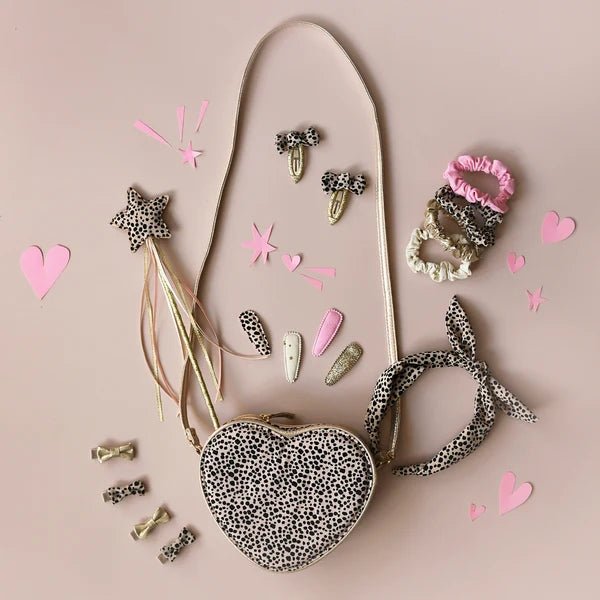 Heart-shaped pouch with leopard print, hair accessories on a pink background