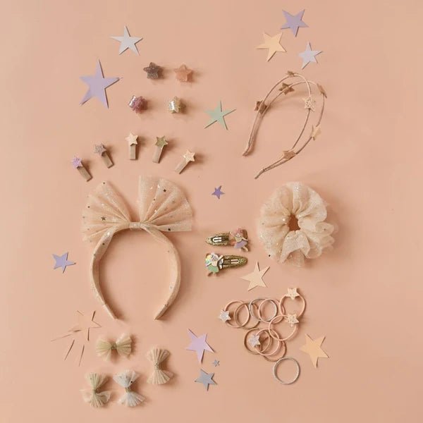 Collection of hair accessories including headbands, scrunchies, and clips on a pink background with star decorations.